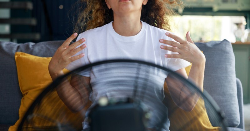A woman sits in front of a cooling fan because Kentucky summers are getting hotter