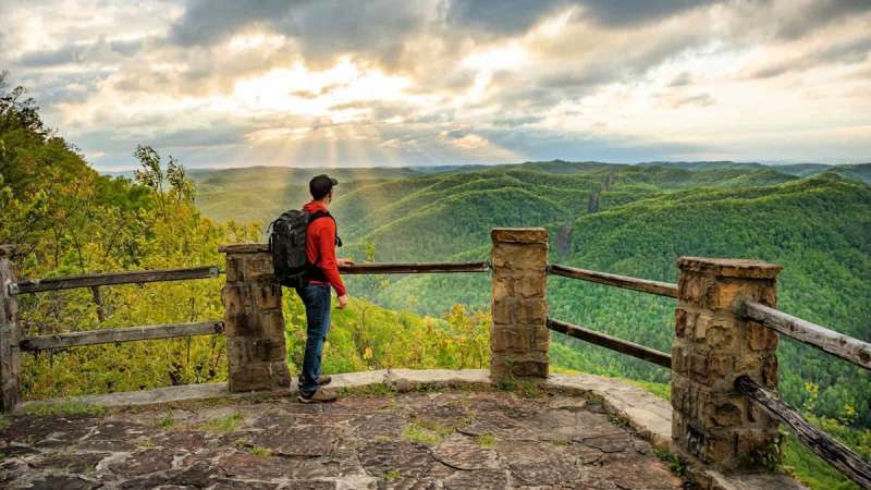 A man at an overlook looking out on the mountains at one of our listed camping spots in Kentucky
